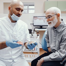 A dentist showing some dentures to an elderly patient