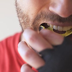 Man putting on yellow and black mouthguard